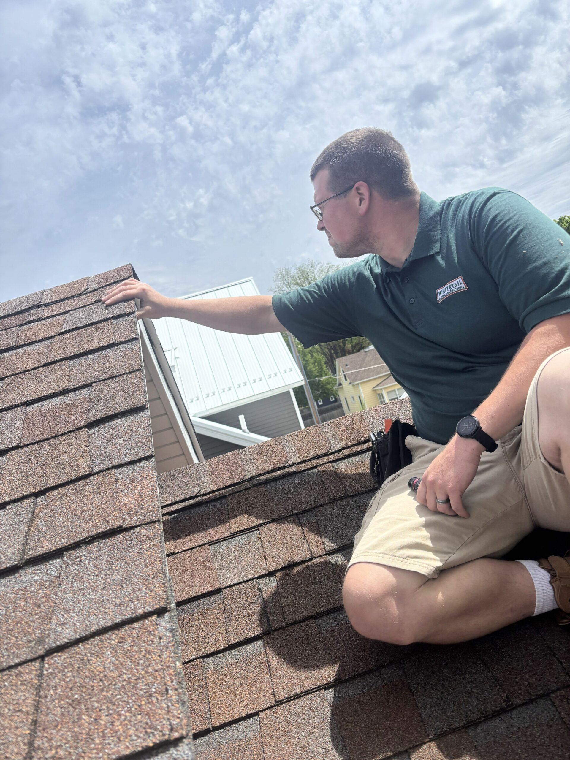 IMG_5574 Professional home inspector examining asphalt roof shingles during a residential roof inspection for Whitetail Home Inspections.